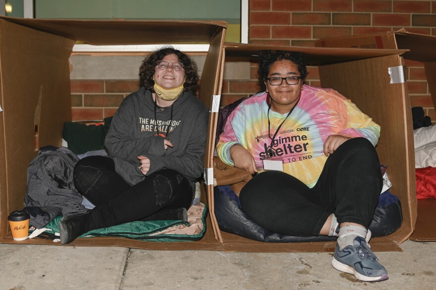 Two participants in the Phoenix Community Development Center's "Gimme Shelter" fundraiser try to get comfortable in their cardboard boxes. 