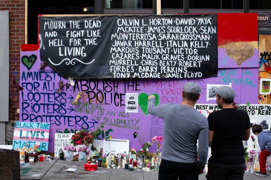 A memorial for Black lives lost grows inside the CHAZ, outside the apparently abandoned East Precinct of the Seattle Police Department.