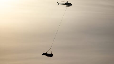 A Bering Air helicopter ferries back sections of flight 445's wings on Saturday, Feb. 8 , 2025.