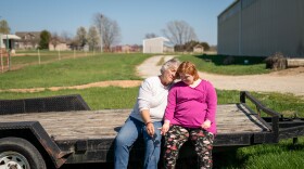 Marilyn and Sammee Lesmeister sit on a trailer parked in the grass. 