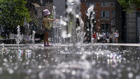 Hattie Hermann, 5, of Washington, plays in a water splash pad among blown bubbles in CityCenterDC, a shopping area downtown, Tuesday, July 11, 2023, in Washington.