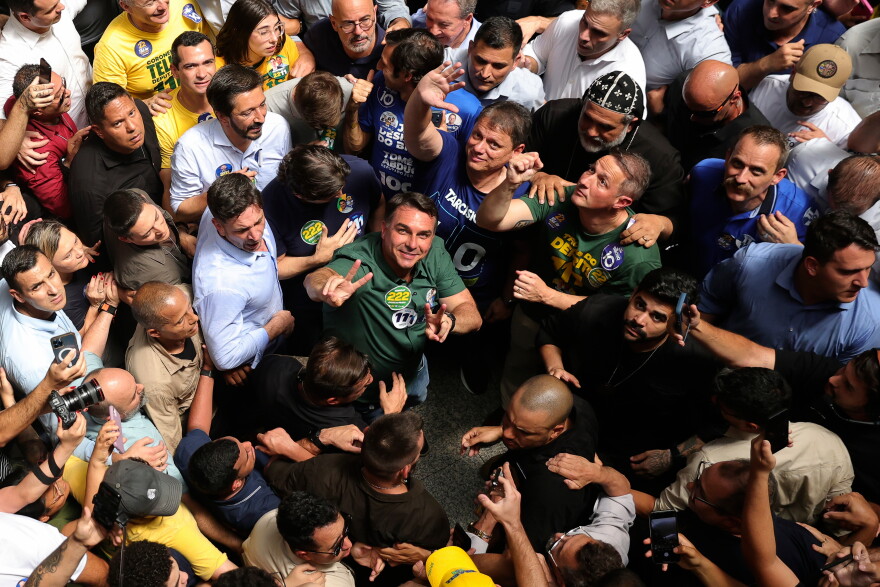Brazilian Sen. Flavio Bolsonaro wearing a green shirt and looking up in the middle of a crowd
