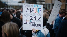 A photo of a sign at a BYU protest that reads 'While at BYU, 74% of LGBT+ students at BYU experience suicidal ideation & 24% of LGBTQIA+ students attempt suicide #thatsnothonor.' 
