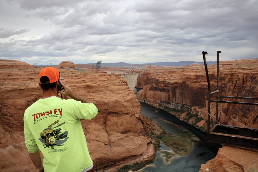 A person on the phone looks out at the Colorado River.
