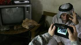 An Iraqi man stretches his eye as a U.S. soldier scans his iris using a biometrics digital system camera during an enlistment program session to join the Sahwa group in Mahmudiyah, in 2008.&nbsp;