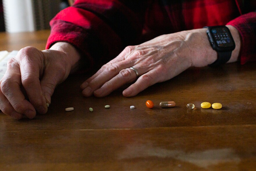Deborah Becket lines up all of her husband Geoff Beckett’s medications and supplements during a March interview. Beckett was one of the customers who was surprised to learn of Kaiser adding its First Fill requirement earlier this year. The Kaiser Permanente of Washington is now removing First Fill. (Credit: Rachel Sun / NWPB)