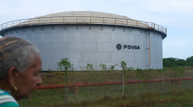 A woman walks near of a oil storage tank of Venezuela's state-run oil company, PDVSA