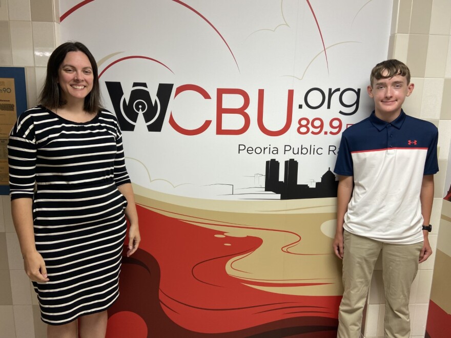 Director of Strategic Communication Gretchen Pearsall (right) and local high school student Brady Reneau stop by to talk about the Peoria County Flag Design Contest.