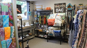A cozy corner of a thrift store with tie-dyed items, handmade rugs, pillows and more. 