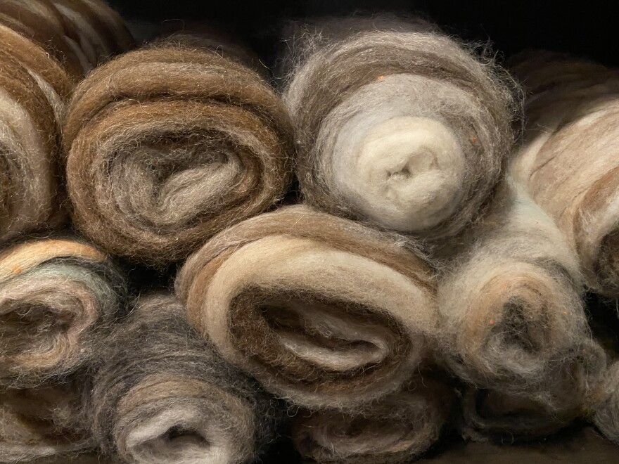 A stack of combed, loosely twisted fiber, or roving, in various shades of tan, brown and grey await the spinner at America's Natural Fiberworks.