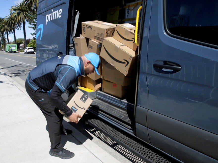 A driver picks up a package while making deliveries for Amazon in Costa Mesa, Calif., on March 23. Amazon is offering to permanent jobs for 125,000 workers it hired to deal with a sharp rise in online shopping during the coronavirus pandemic.