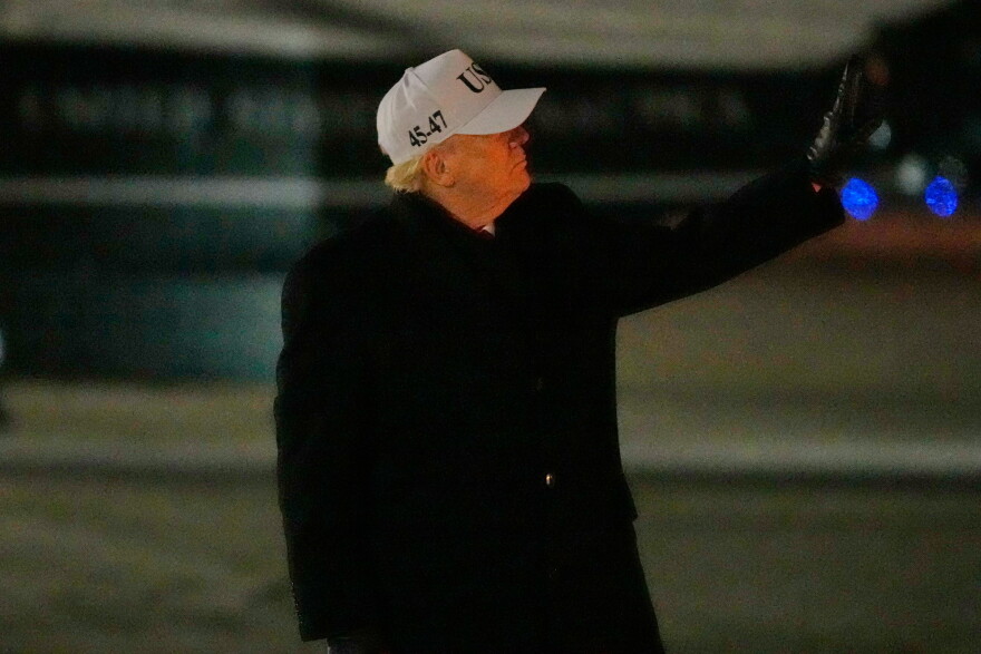 President Donald Trump gestures to a person walking down the stairs behind him as he arrives on Air Force One, Tuesday, Jan. 27, 2026, at Joint Base Andrews, Md., after returning from a trip to Iowa. (AP Photo/Mark Schiefelbein)