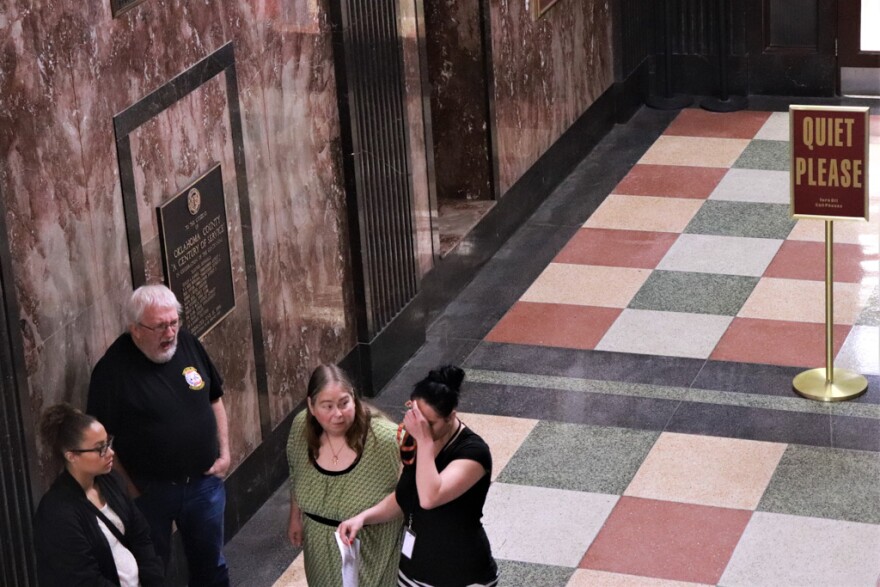 A group of people stand outside a courtroom at the Oklahoma County courthouse.