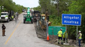 FILE - Workers install a sign reading "Alligator Alcatraz" at the entrance to the migrant detention facility at Dade-Collier Training and Transition facility, July 3, 2025, in Ochopee, Fla. (AP Photo/Rebecca Blackwell, file)