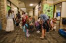 Children with backpacks and adults gather in a hallway.