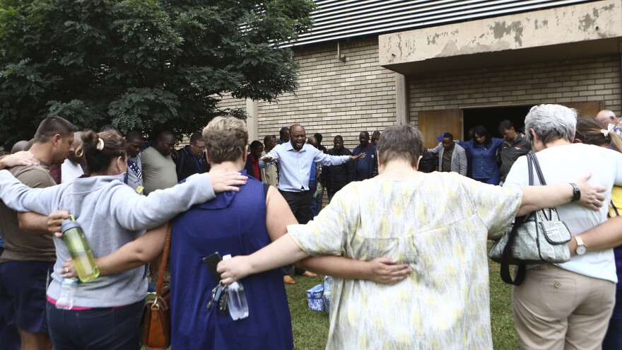 A pastor leads people in prayer Friday at the site of a walkway collapse at the Driehoek high school in Vanderbijlpark, South Africa.