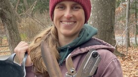 A woman holding gardening tools.
