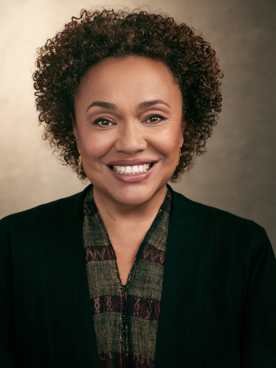 A portrait of Maria Rosario Jackson in a black blazer and gold earrings