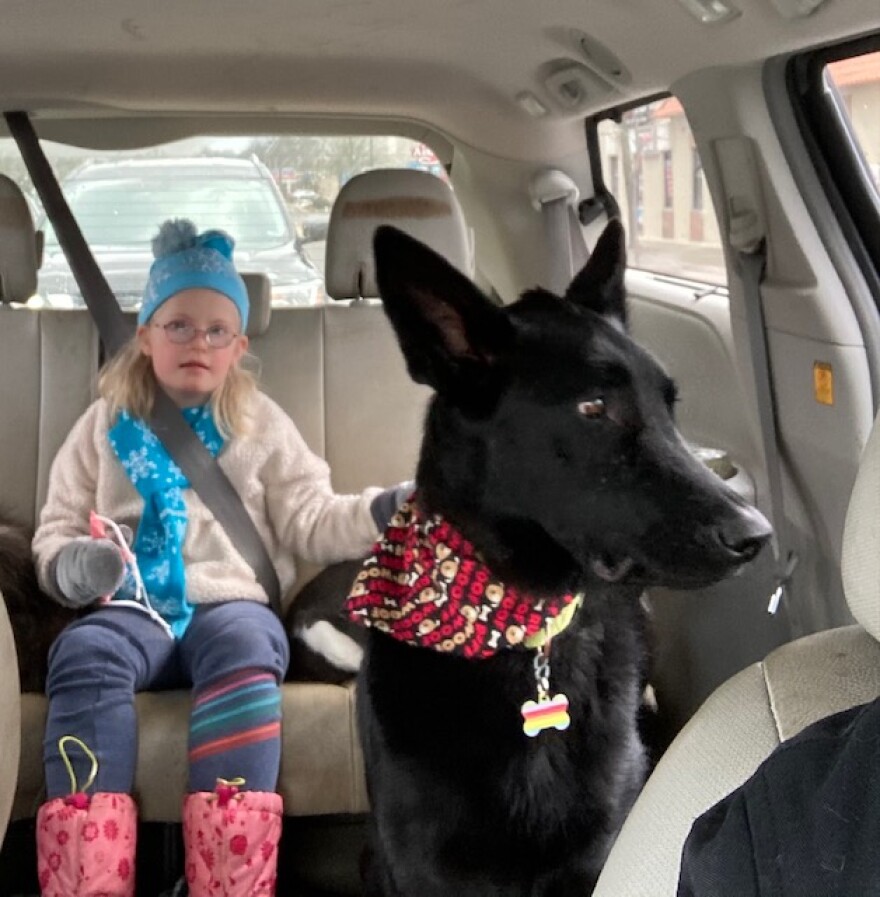 Eight-year-old Lyra Christensen rides in the back of the car with her dog. Lyra loves playing the harmonica after school, which often makes her dog howl.