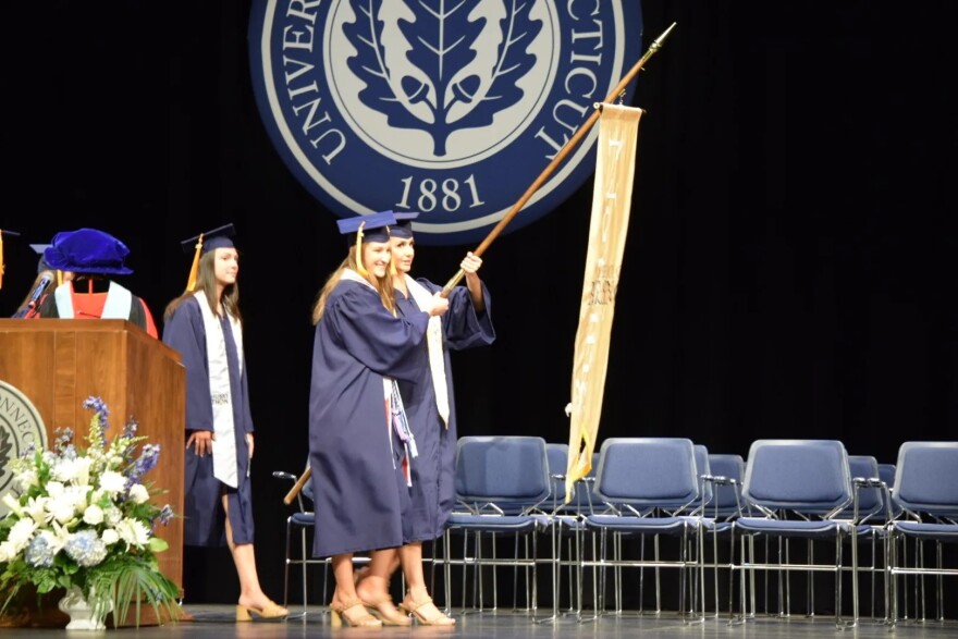 Three UCONN students carry the School of Nursing flag