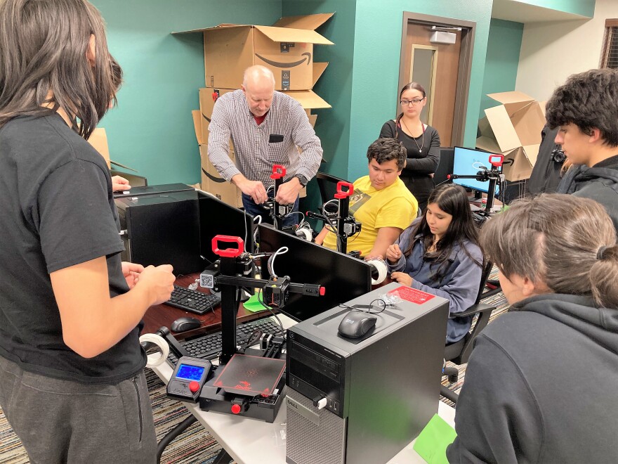 Tom Bachinski, CEO of Simpson Electric, teaches high schoolers how to set up and use a 3D printer.