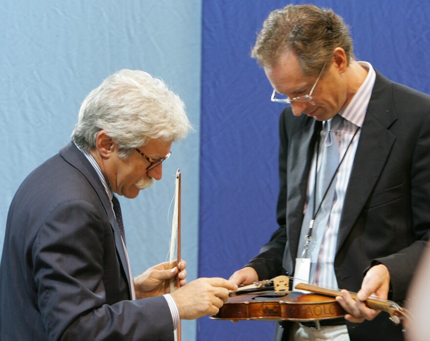 Appraisers Fred Oster (left) and David Bonsey, review a 1920 French violin at an <em>Antiques Roadshow</em> event in Los Angeles in 2005. Many stringed instruments throughout history have been made using small amounts of ivory.