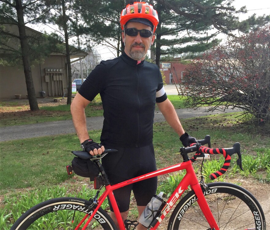 Man in bike gear standing with bike