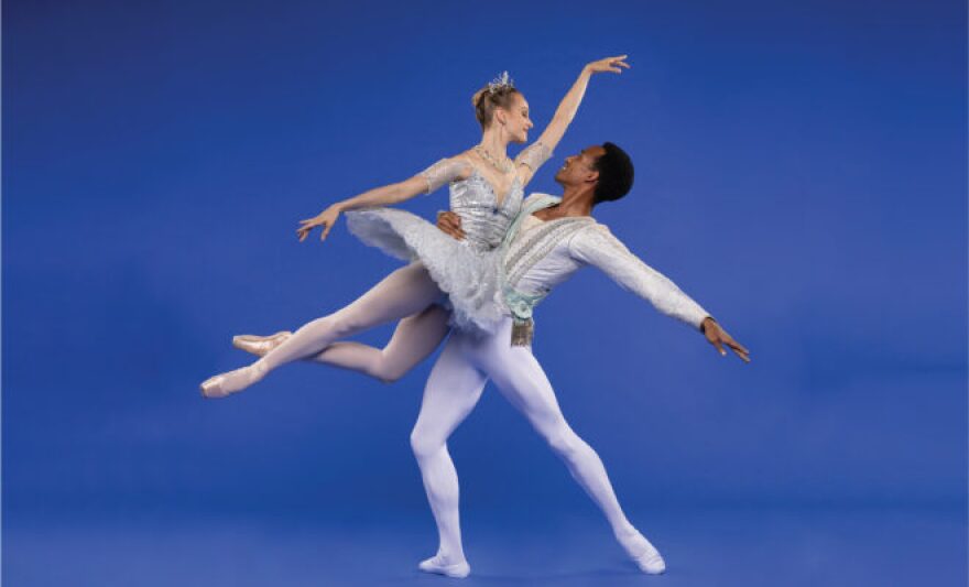 A ballet dancer holding a ballerina in the air, looking at each other