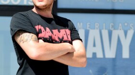 Zachary Gallegos, 23, stands guard outside the Armed Services Recruiting Center on Thursday in Sioux Falls, South Dakota. The Pentagon has asked such self-appointed "armed citizens" to leave, citing security concerns.