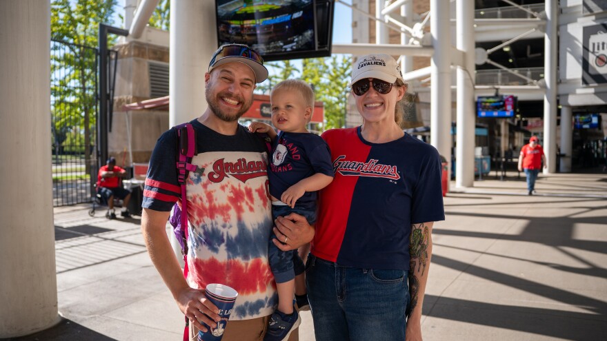 Family with small child smile at baseball game.