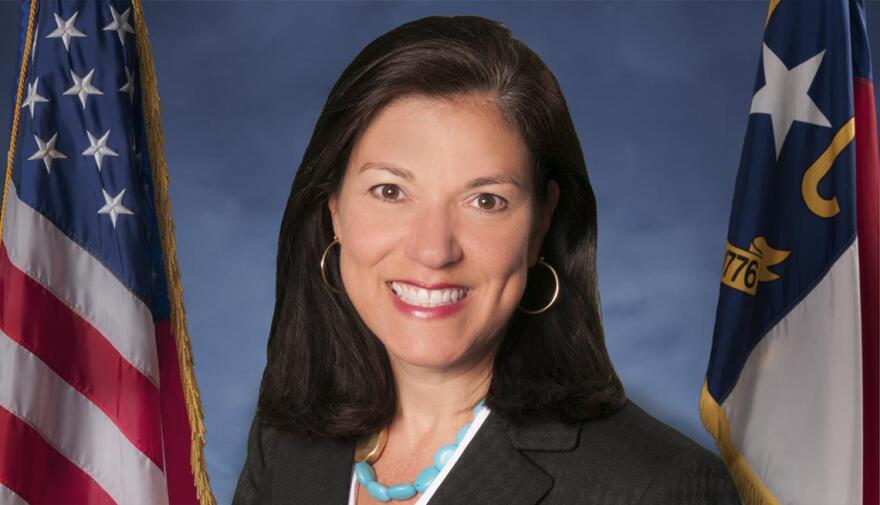 photo of Pamela Cashwell wearing blazer and positioned between U.S. and North Carolina state flags