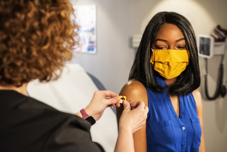 A masked woman receives a shot.