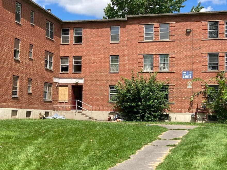 A three-story brick building with some trash piled out front.