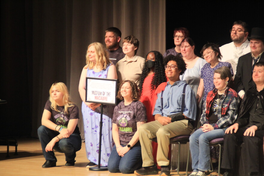 A theater cast is shown posing for a photograph. 