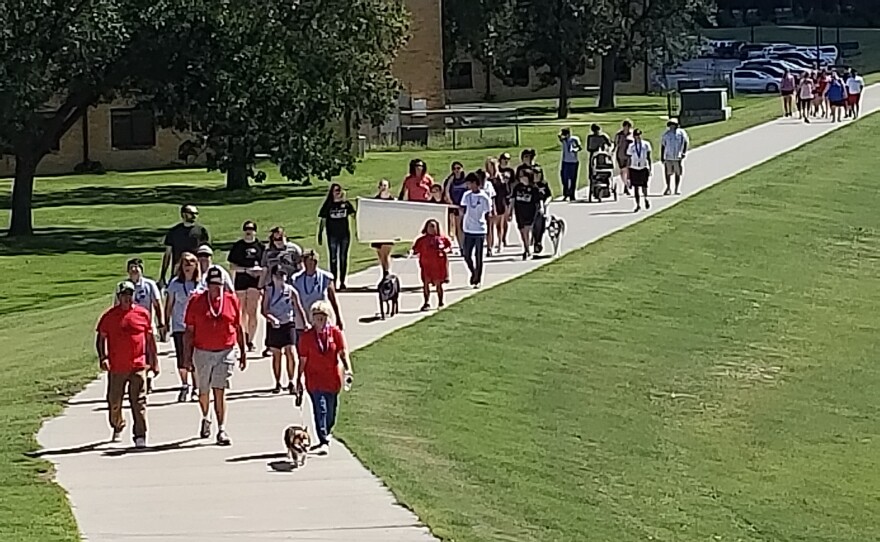 People walk along a sidewalk during a suicide prevention walk in Hays.