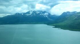 Blue-green lake surrounded by mountains from the air