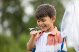 boy with dragonfly on holding hand in the nature background
