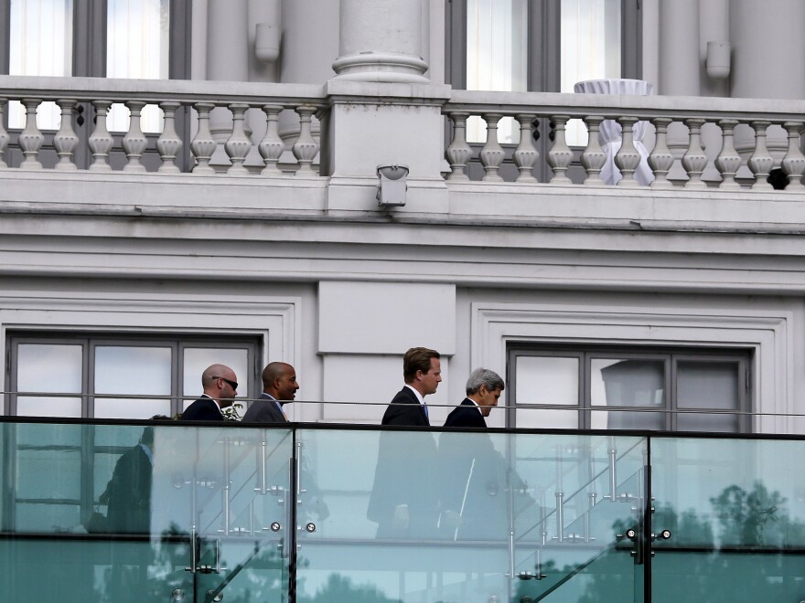 Secretary of State John Kerry (right) walks using crutches Thursday at the garden of the hotel where the Iran nuclear talks are being held in Vienna.