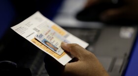 FILE - An election official checks a voter's photo identification at an early voting polling site in Austin, Texas, Feb. 26, 2014. (AP Photo/Eric Gay, File)