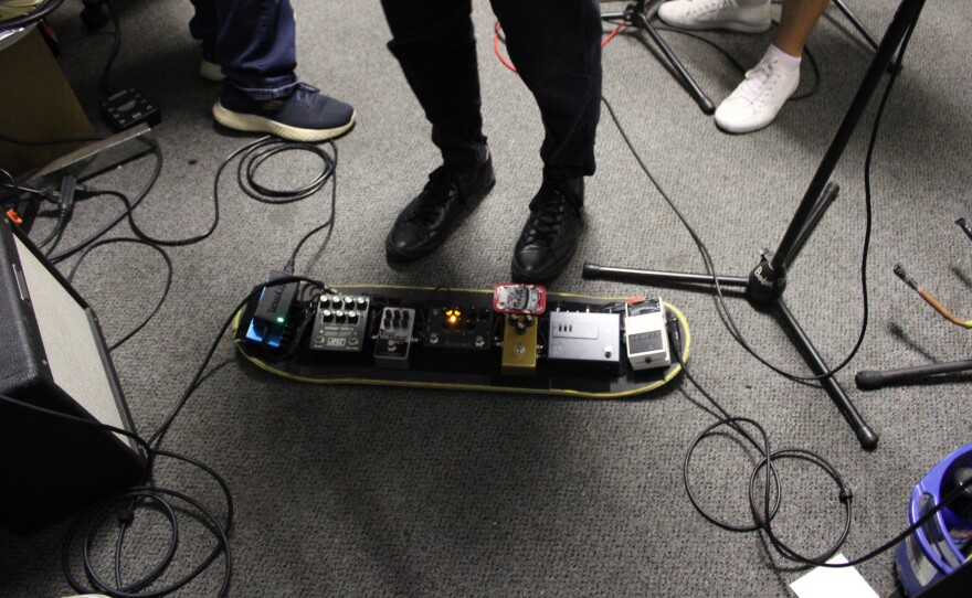 Different pedals are set up on a skateboard deck.