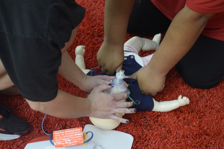 two people practice reviving a practice baby dummy