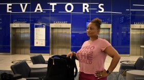 A woman in a pink outfit stands next to her luggage in the main terminal of Tampa International Airport
