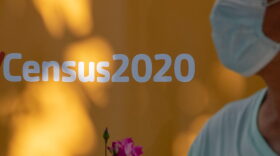 A man wearing a facemask walks past a sign encouraging people to complete the 2020 US Census, in Los Angeles, California amid the COVID-19 pandemic.