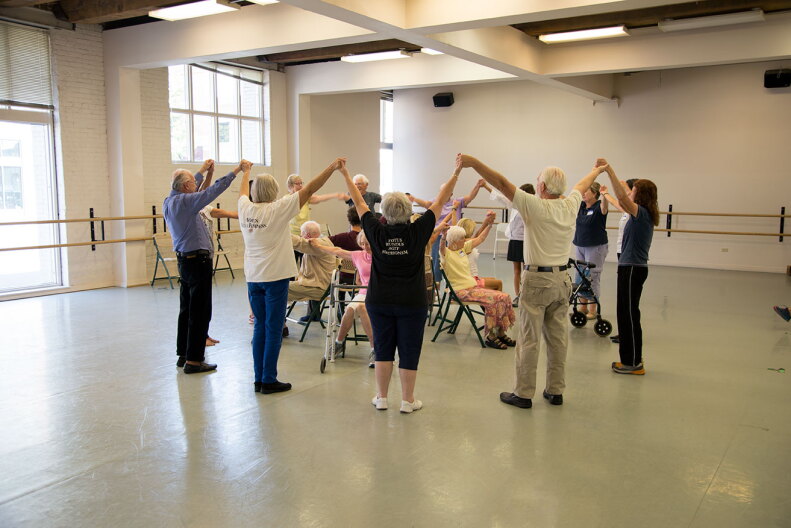 Members of a  "Dance for Parkinson's Idaho" class stand in a circle holding hands.