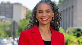 African American woman wearing red blazer smiles at camera