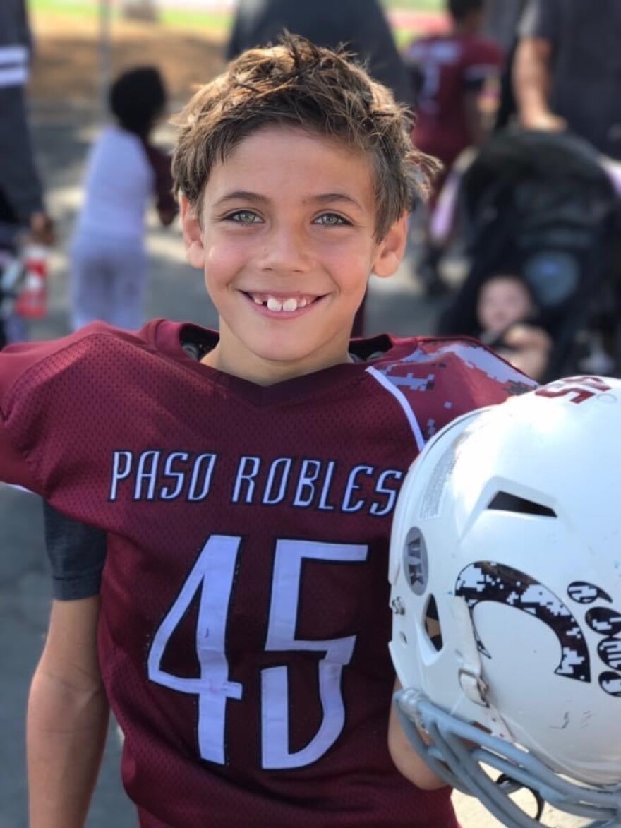 A boy wearing a football jersey with the name 'Paso Robles' and the number '45' smiles.