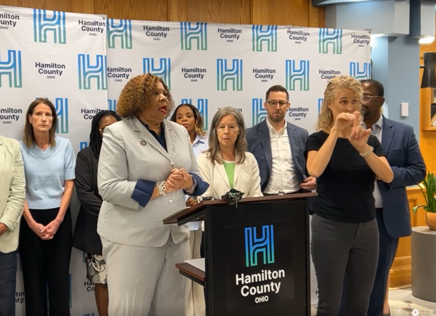 two women stand at a podium with people behind them