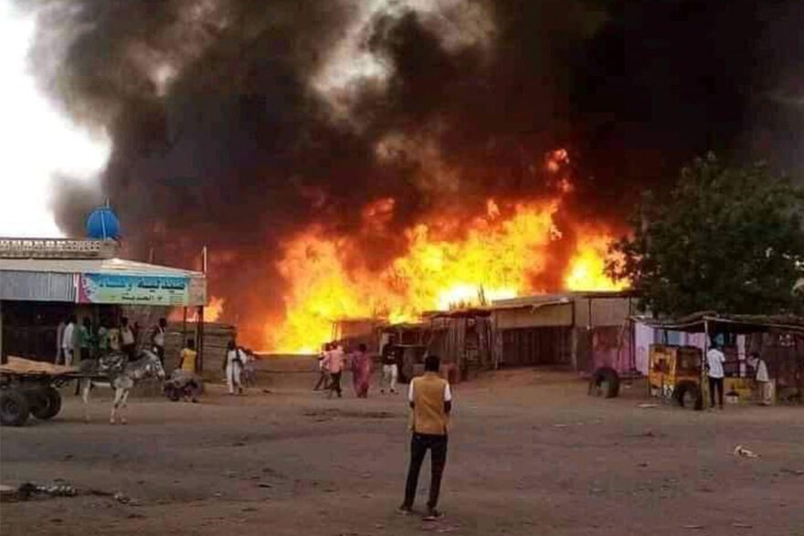 A man stands by as a fire rages in a livestock market area in al-Fasher, the capital of Sudan's North Darfur state in the aftermath of bombardment by the paramilitary Rapid Support Forces (RSF).