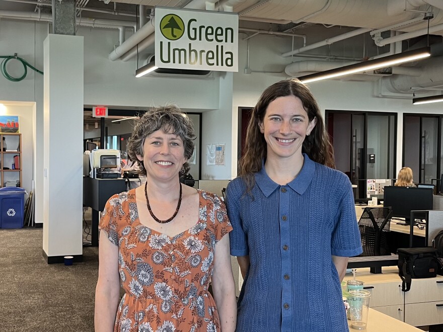Two people stand in an office under a sign that says Green Umbrella.
