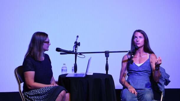 Erin interviews Melissa, seated by a black table with two microphones